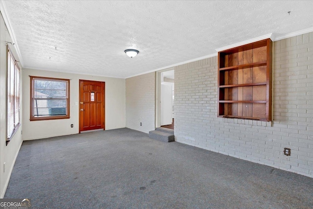 unfurnished living room featuring crown molding, a textured ceiling, brick wall, and dark colored carpet