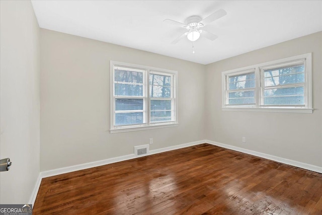 empty room featuring dark wood-type flooring, ceiling fan, and a healthy amount of sunlight