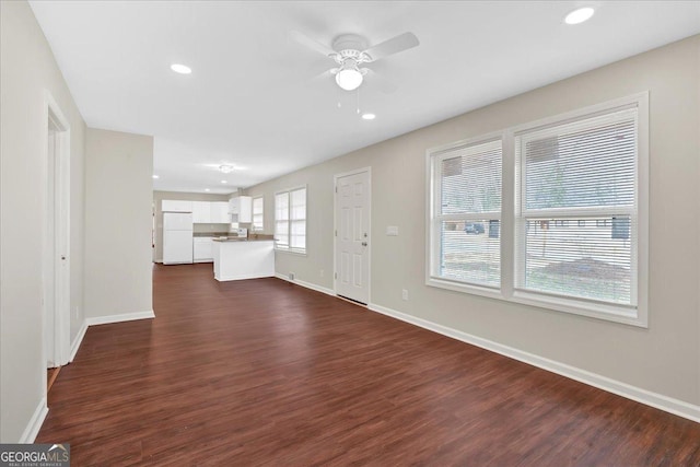 unfurnished living room with dark hardwood / wood-style flooring and ceiling fan