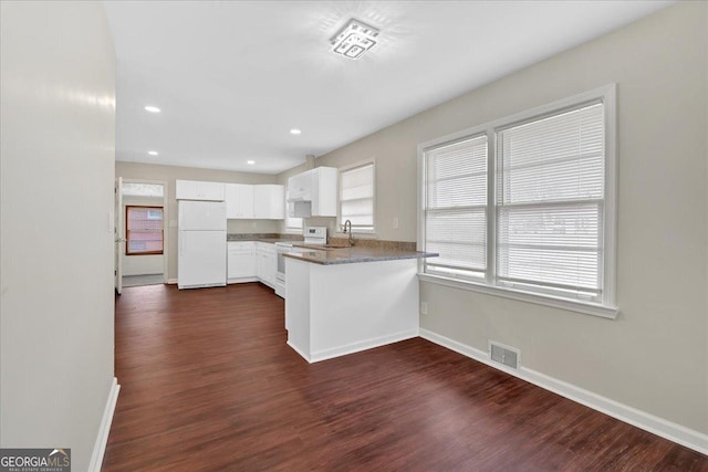 kitchen with sink, white appliances, white cabinetry, light stone counters, and kitchen peninsula