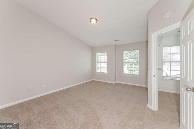 spare room with vaulted ceiling and light colored carpet