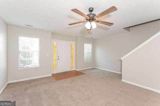 entryway with light carpet, ceiling fan, and a textured ceiling