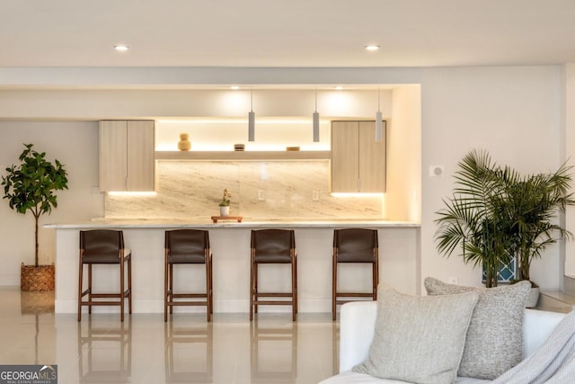 kitchen featuring tasteful backsplash, light brown cabinets, and a kitchen bar