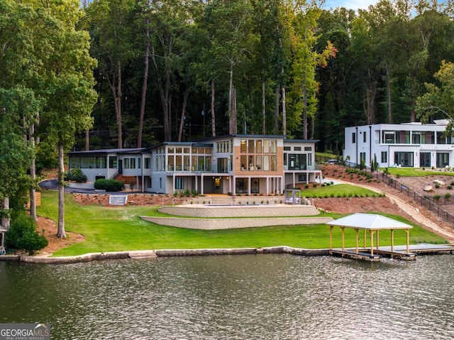 back of house with a water view, a yard, and a sunroom