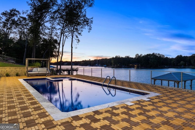 pool at dusk with a patio and a water view