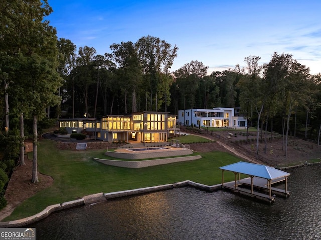 back house at dusk with a water view and a yard