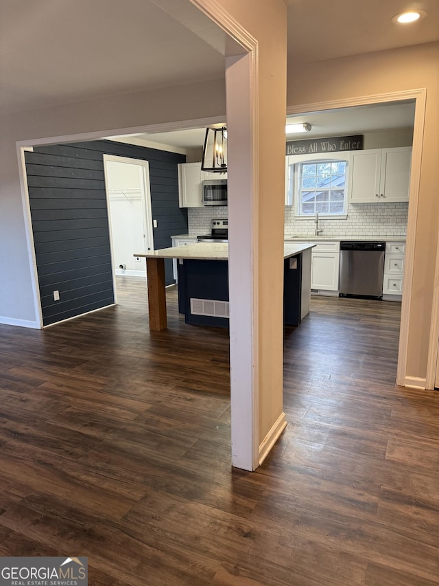 kitchen with dark wood-type flooring, sink, white cabinetry, hanging light fixtures, and appliances with stainless steel finishes