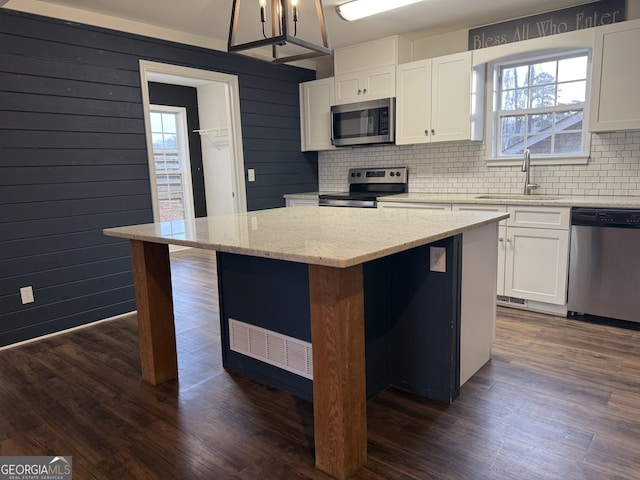 kitchen with white cabinetry, sink, stainless steel appliances, and a center island