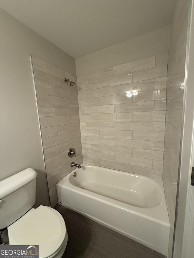 bathroom featuring toilet and tiled shower / bath