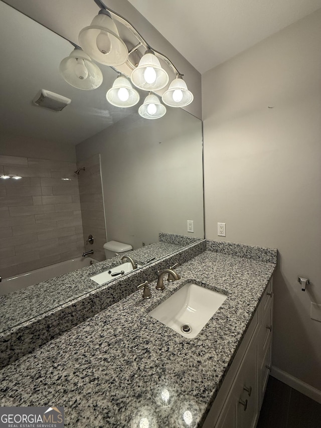 full bathroom featuring vanity, tiled shower / bath combo, and toilet