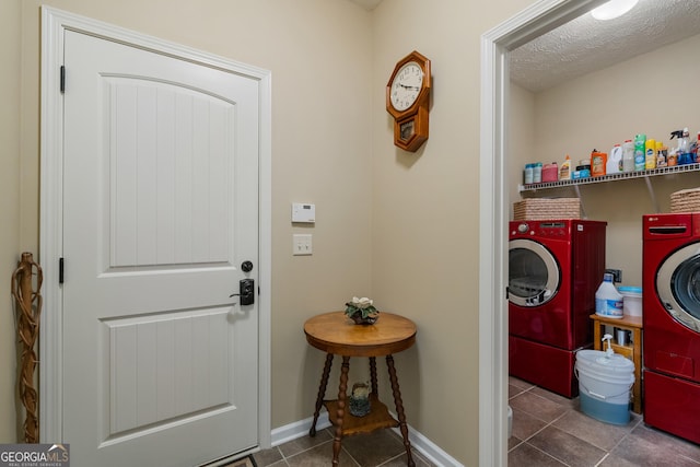 clothes washing area with dark tile patterned flooring, washer and clothes dryer, and a textured ceiling