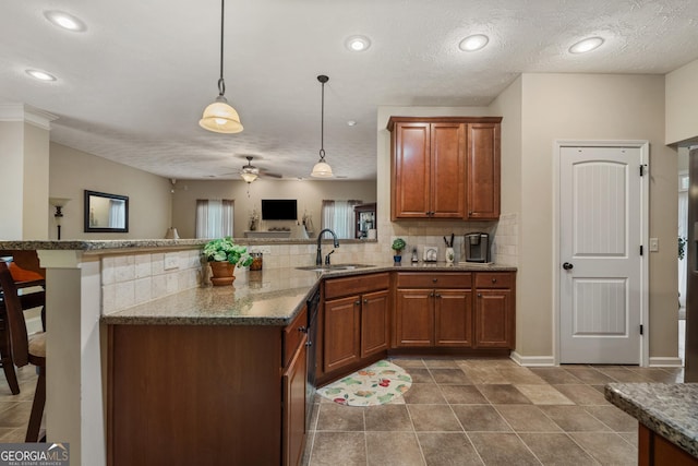 kitchen featuring stone counters, decorative light fixtures, sink, kitchen peninsula, and a textured ceiling