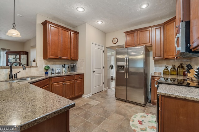 kitchen featuring pendant lighting, tasteful backsplash, sink, stainless steel appliances, and a textured ceiling