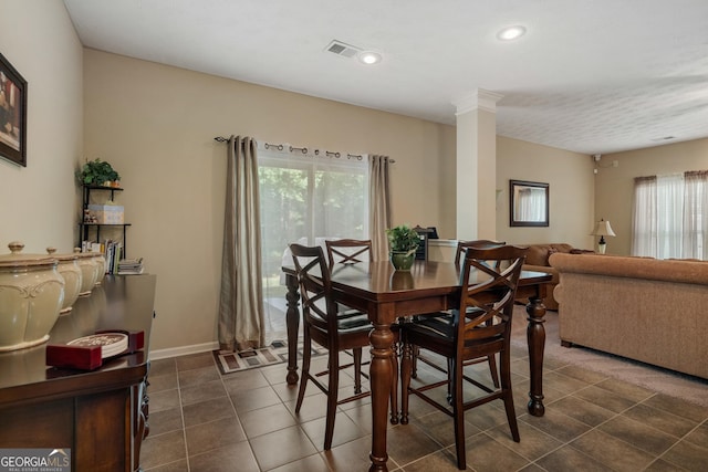 dining area with decorative columns and dark tile patterned flooring