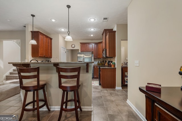 kitchen featuring appliances with stainless steel finishes, decorative light fixtures, tasteful backsplash, a kitchen bar, and kitchen peninsula