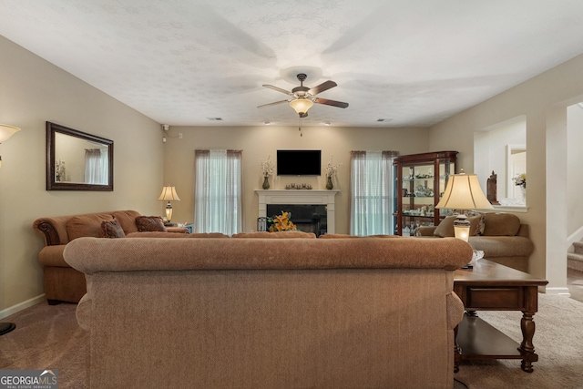 carpeted living room with a textured ceiling and ceiling fan