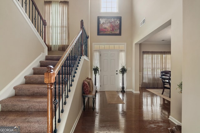 entryway with a high ceiling, ornamental molding, and dark hardwood / wood-style flooring