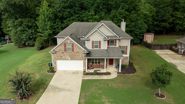 view of front of property featuring a garage, covered porch, and a front yard