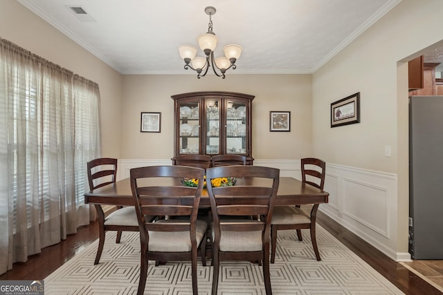 dining room with ornamental molding, wood-type flooring, and a chandelier