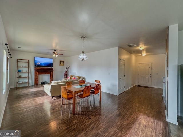 dining room with a barn door, dark hardwood / wood-style floors, and ceiling fan with notable chandelier