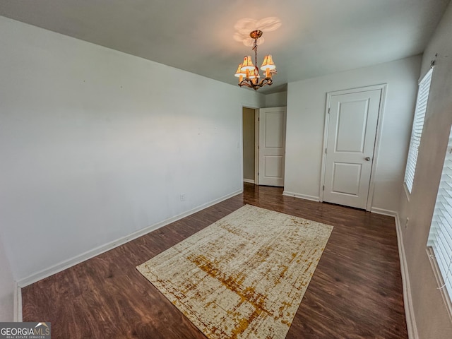 unfurnished bedroom with dark hardwood / wood-style floors and a notable chandelier