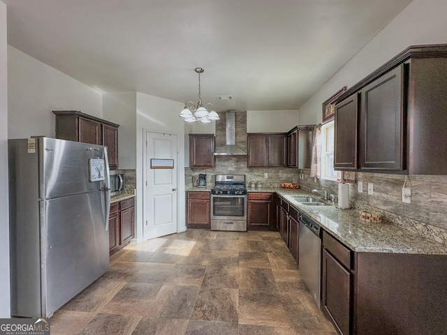 kitchen with sink, appliances with stainless steel finishes, hanging light fixtures, dark brown cabinetry, and wall chimney exhaust hood