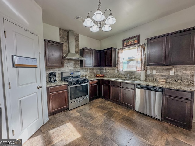 kitchen featuring wall chimney exhaust hood, sink, hanging light fixtures, appliances with stainless steel finishes, and light stone countertops