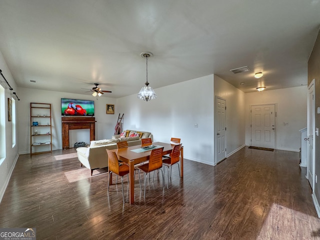 dining area with dark hardwood / wood-style floors and ceiling fan with notable chandelier