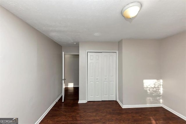 unfurnished bedroom with dark hardwood / wood-style floors and a closet