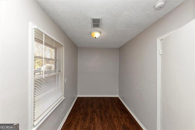 empty room featuring dark wood-type flooring and a textured ceiling