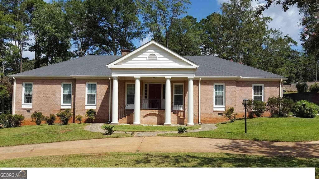 greek revival inspired property with a porch and a front lawn