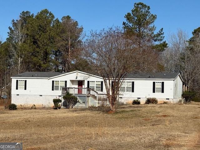 manufactured / mobile home featuring a wooden deck and a front yard