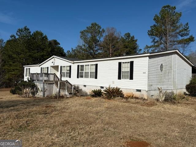 manufactured / mobile home with a deck and a front lawn