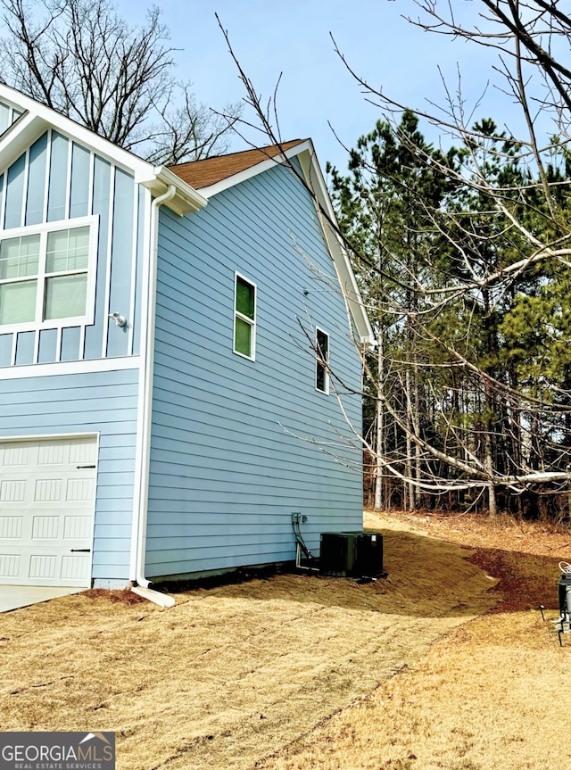 view of home's exterior with central AC and a garage