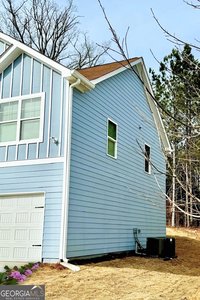 view of side of property featuring a garage and cooling unit