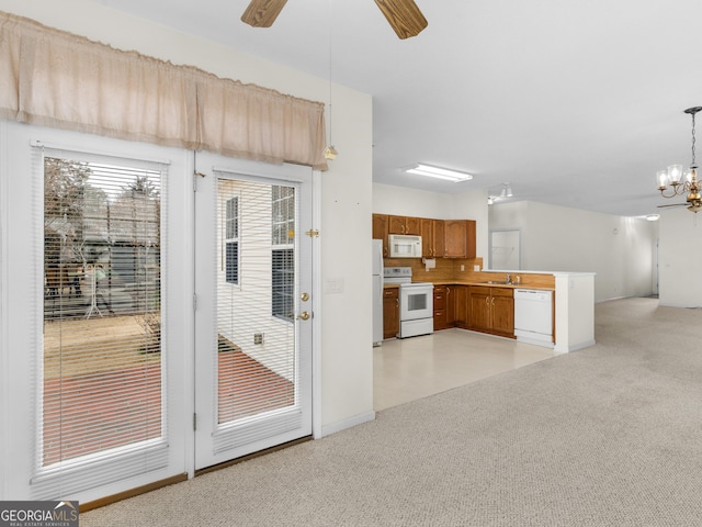 interior space featuring hanging light fixtures, white appliances, ceiling fan with notable chandelier, and light colored carpet