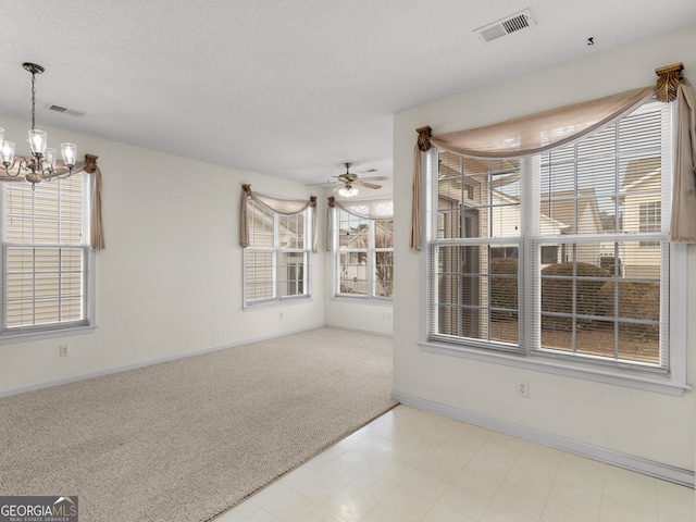 spare room featuring light colored carpet, plenty of natural light, and ceiling fan with notable chandelier