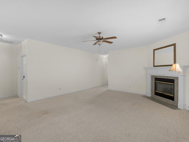 unfurnished living room featuring ceiling fan, a tiled fireplace, and light carpet