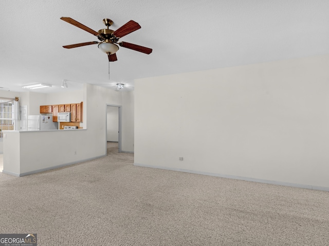 unfurnished living room featuring ceiling fan and light colored carpet