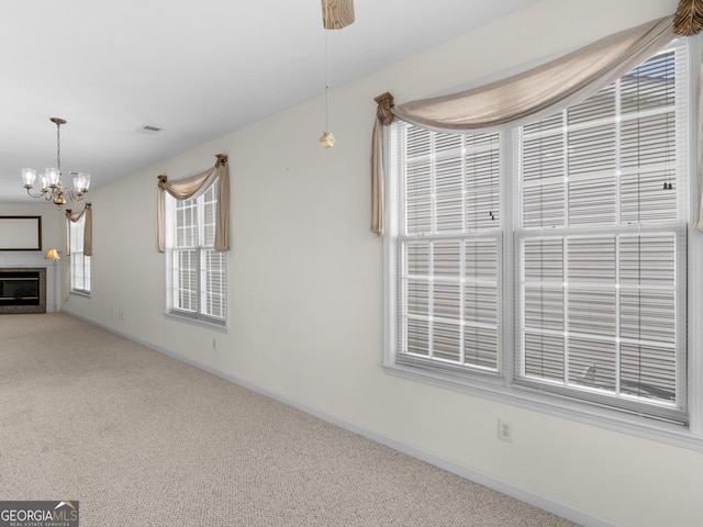 unfurnished living room with ceiling fan with notable chandelier and carpet