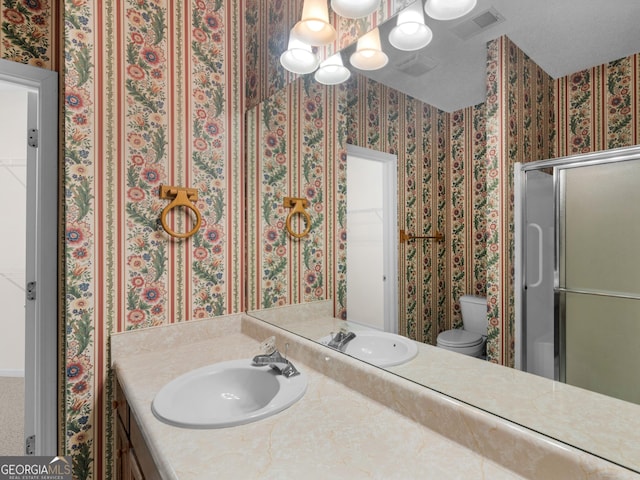 bathroom featuring a shower with door, vanity, an inviting chandelier, and toilet