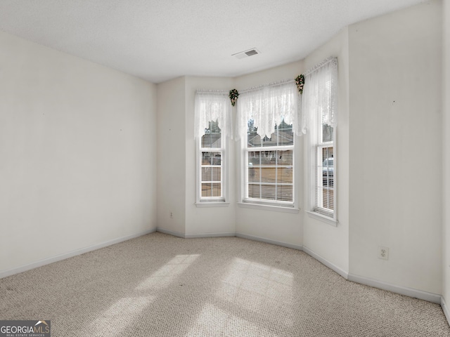 carpeted empty room with a textured ceiling