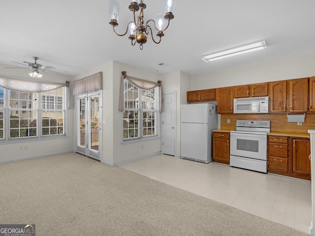 kitchen featuring light carpet, hanging light fixtures, white appliances, and ceiling fan with notable chandelier