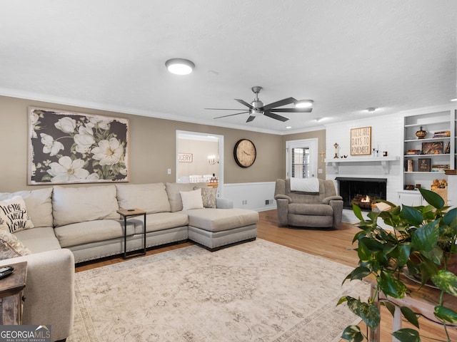 living room with crown molding, hardwood / wood-style flooring, a fireplace, and ceiling fan