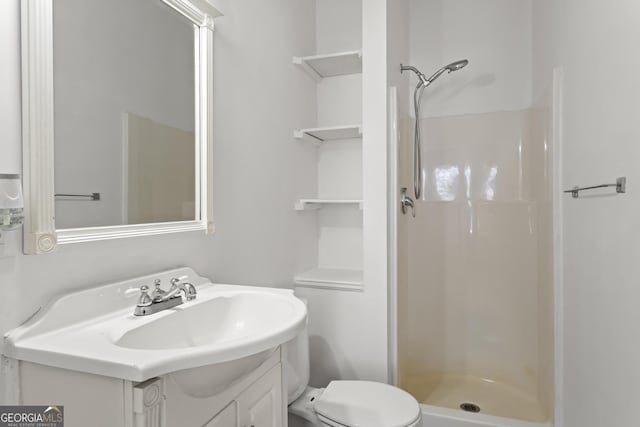 bathroom with vanity, toilet, and a shower