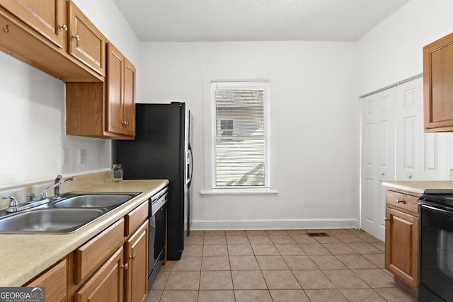 kitchen featuring sink, light tile patterned floors, and black appliances