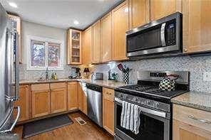 kitchen with appliances with stainless steel finishes, dark hardwood / wood-style flooring, and backsplash