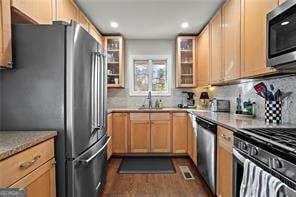 kitchen featuring dark wood-type flooring, sink, tasteful backsplash, light brown cabinets, and appliances with stainless steel finishes