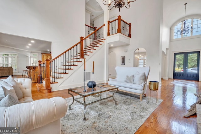 living room featuring a towering ceiling, a chandelier, and light hardwood / wood-style floors