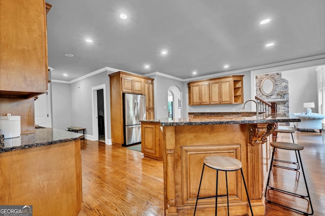 kitchen with stainless steel fridge, a breakfast bar, light hardwood / wood-style floors, and kitchen peninsula